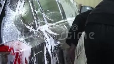 洗车一个洗车工洗车.. 一个男人用泡沫海绵洗汽车。 特写镜头。